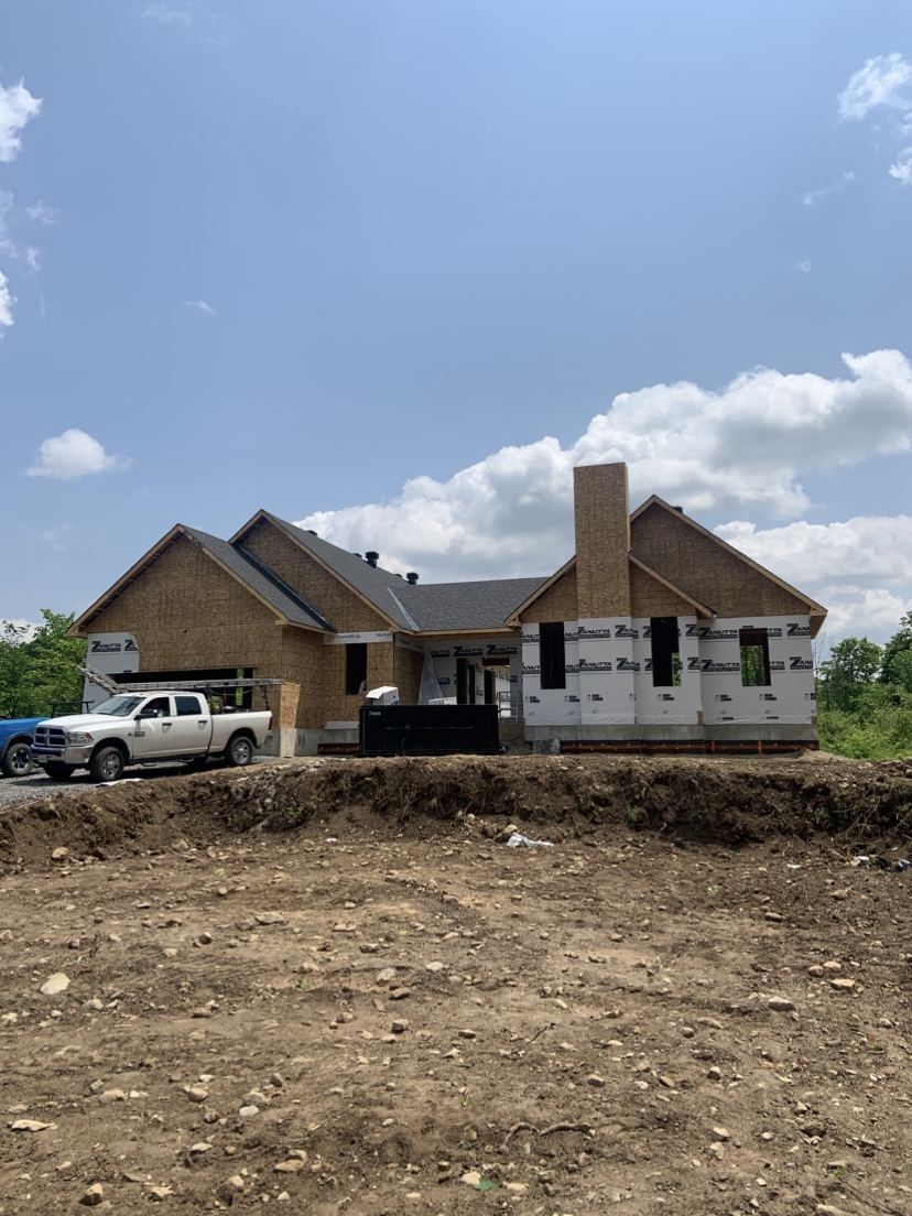 A new house with a stone chimney, a Sherrer truck in the drive