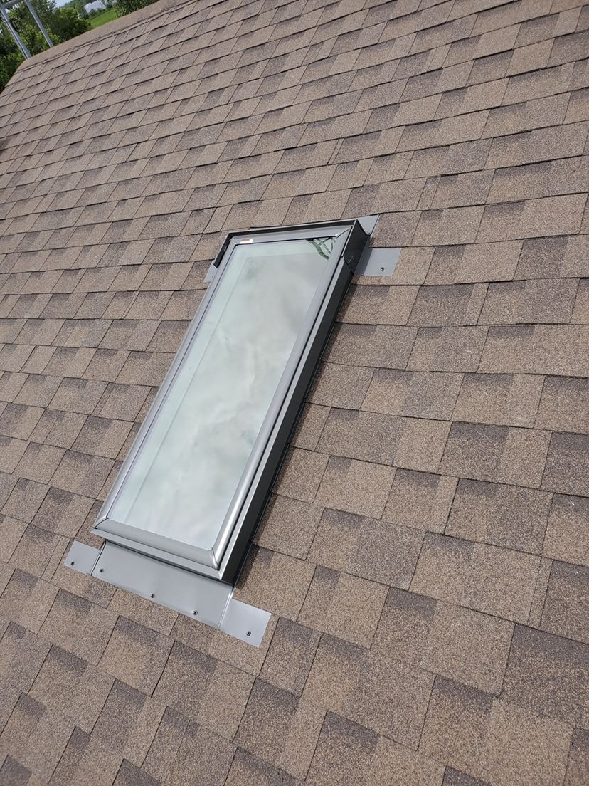 A skylight flashed into a brown shingle roof